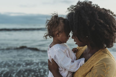 Side view of mother and daughter in water