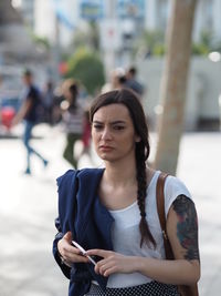 Portrait of young woman looking at city street