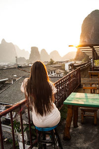 Rear view of woman sitting on seat against mountains