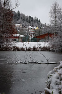 Snow covered house by lake against building