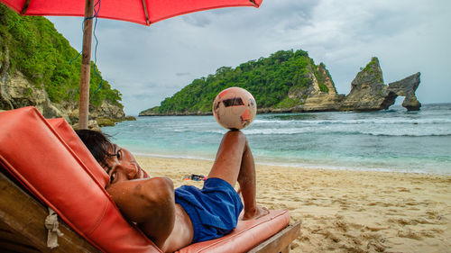 Man lying on beach against sky