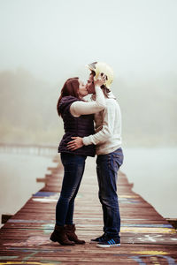 Full length of woman standing on wooden pier in front of lake