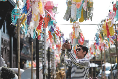 Man photographing colorful lanterns in city