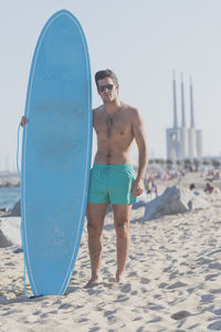 Shirtless man with surfboard at beach