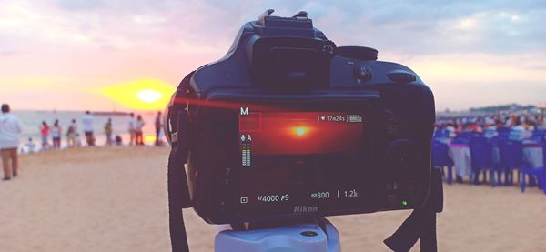 People photographing on beach during sunset