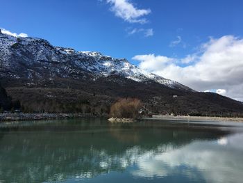 Scenic view of lake by snowcapped mountains against sky