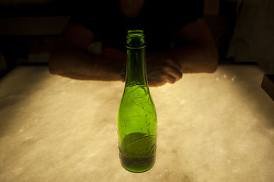 Close-up of hand holding glass bottle on table