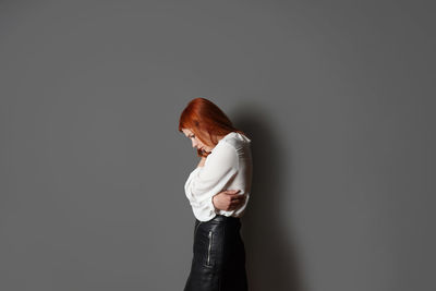 Portrait of young woman standing against black background