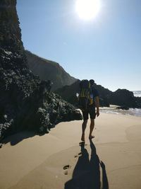 Man standing on mountain against sky on sunny day