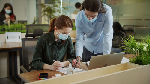 Woman using phone while sitting on table