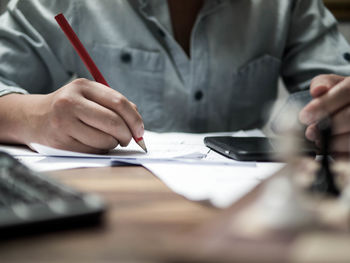 Midsection of businesswoman working at desk in office