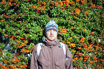 Portrait of young man standing by flowering plants