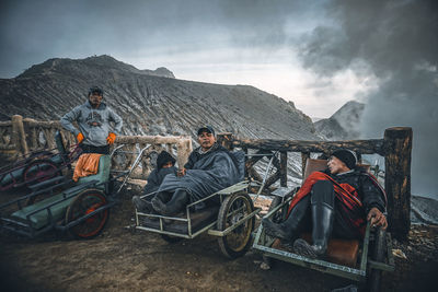 People sitting on mountain road against sky