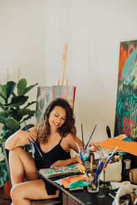 Female artist holding paintbrushes while working on her painting