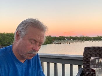 Portrait of man on railing against sky during sunset