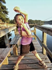 Young woman standing on footbridge against lake