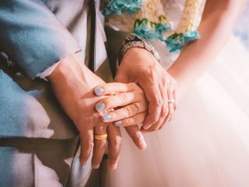 Midsection of couple holding hands at wedding