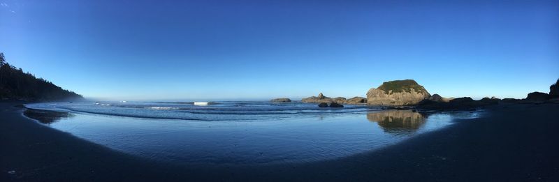 Panoramic view of beach against clear blue sky