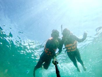 Portrait of man and woman taking selfie with monopod while doing scuba diving in sea