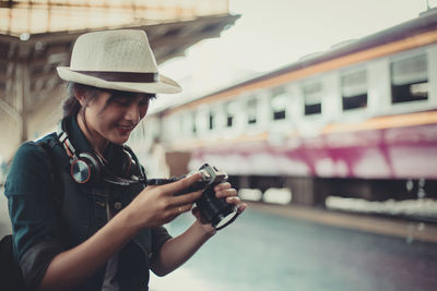 Young woman using mobile phone while standing on camera