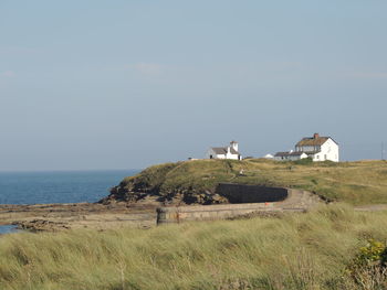 House on field by sea against sky