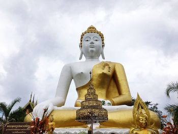 Low angle view of buddha statue in temple against sky