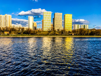 River by buildings against blue sky