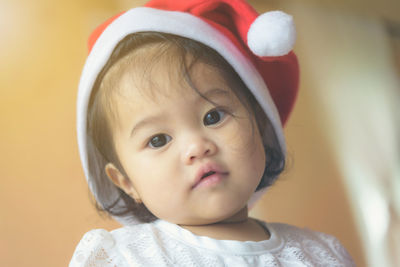 Close-up portrait of cute baby girl wearing santa hat