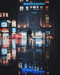 Reflection of man walking in illuminated city