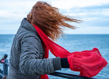 A woman stands by the sea in strong winds. concept stormy weather