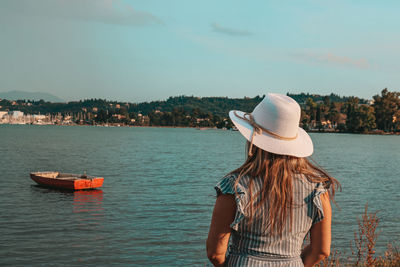 Rear view of a woman watching sea and red boat