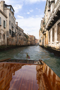 Canal amidst buildings in city against sky