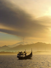 Silhouette of boat sailing at sunset