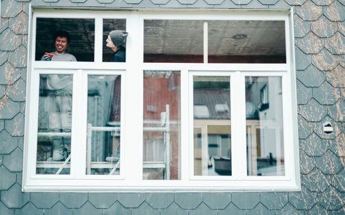 Two happy people are repairing a window. person