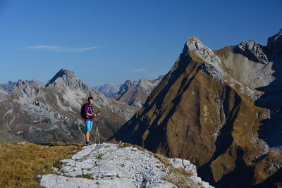 Man standing on rocks by mountain against sky