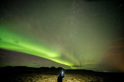 Man standing on landscape against star field at night