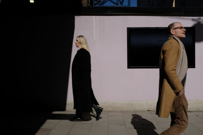 Rear view of women standing against wall