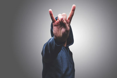 Midsection of person wearing hat against gray background