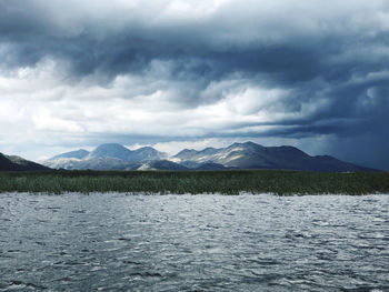 Scenic view of lake by mountains against sky