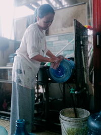 A woman is washing gallon using a gallon washing machine during the day in solear city