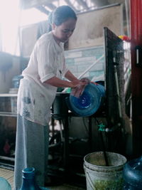 A woman is washing gallon using a gallon washing machine during the day in solear city