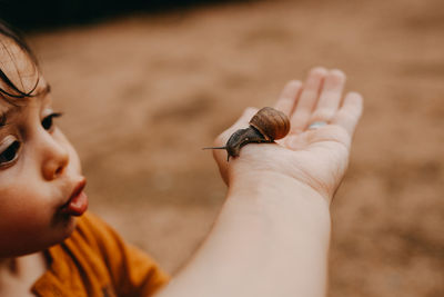 Close-up of baby hand holding small outdoors