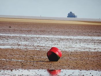 Red umbrella on beach against clear sky