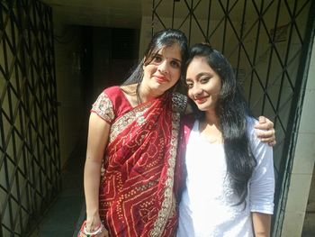 Portrait of female friends smiling while standing by gate