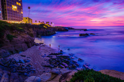 Scenic view of sea and buildings against sky at sunset