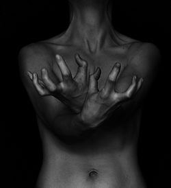 Midsection of naked sensual woman gesturing against black background