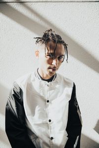 Portrait of young man standing against white wall