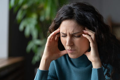 Unhappy businesswoman suffer from strong headache touch temples exhausted from stress at workplace