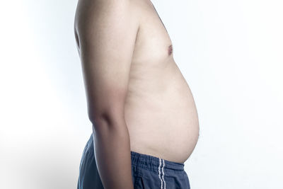 Midsection of shirtless man standing against white background