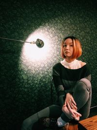 Young woman sitting in illuminated room